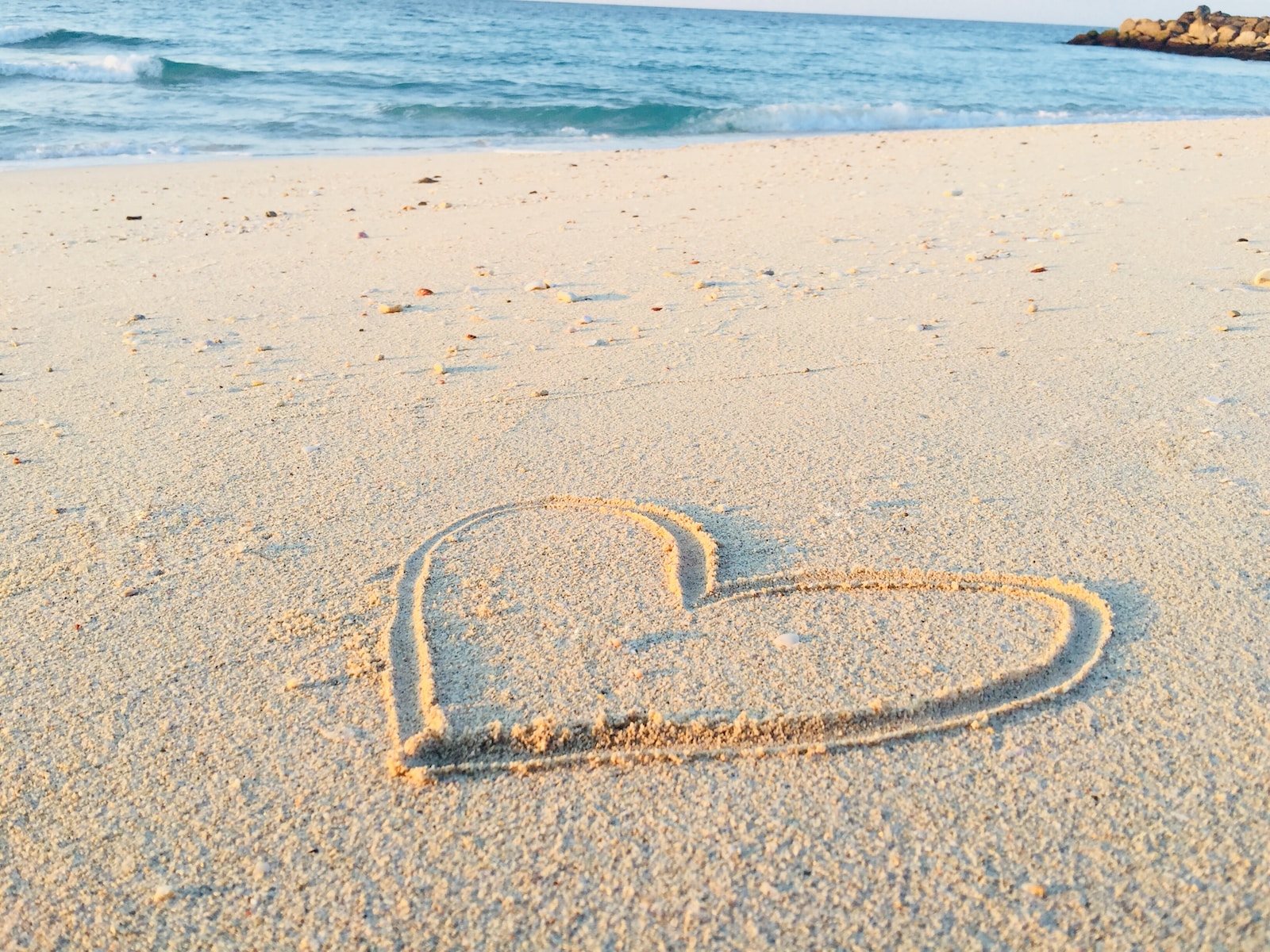 heart drawn on sand during daytime